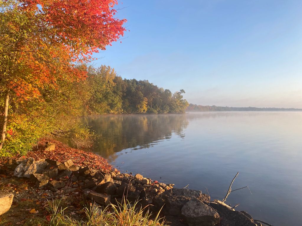 Serene lake with autumn foliage and clear sky.