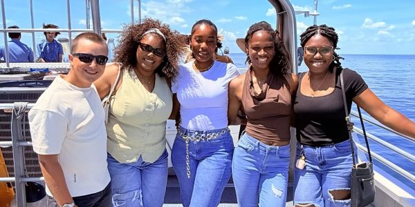 Group of friends posing on a boat with ocean background.