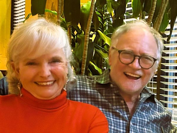 Smiling elderly couple sitting together indoors.