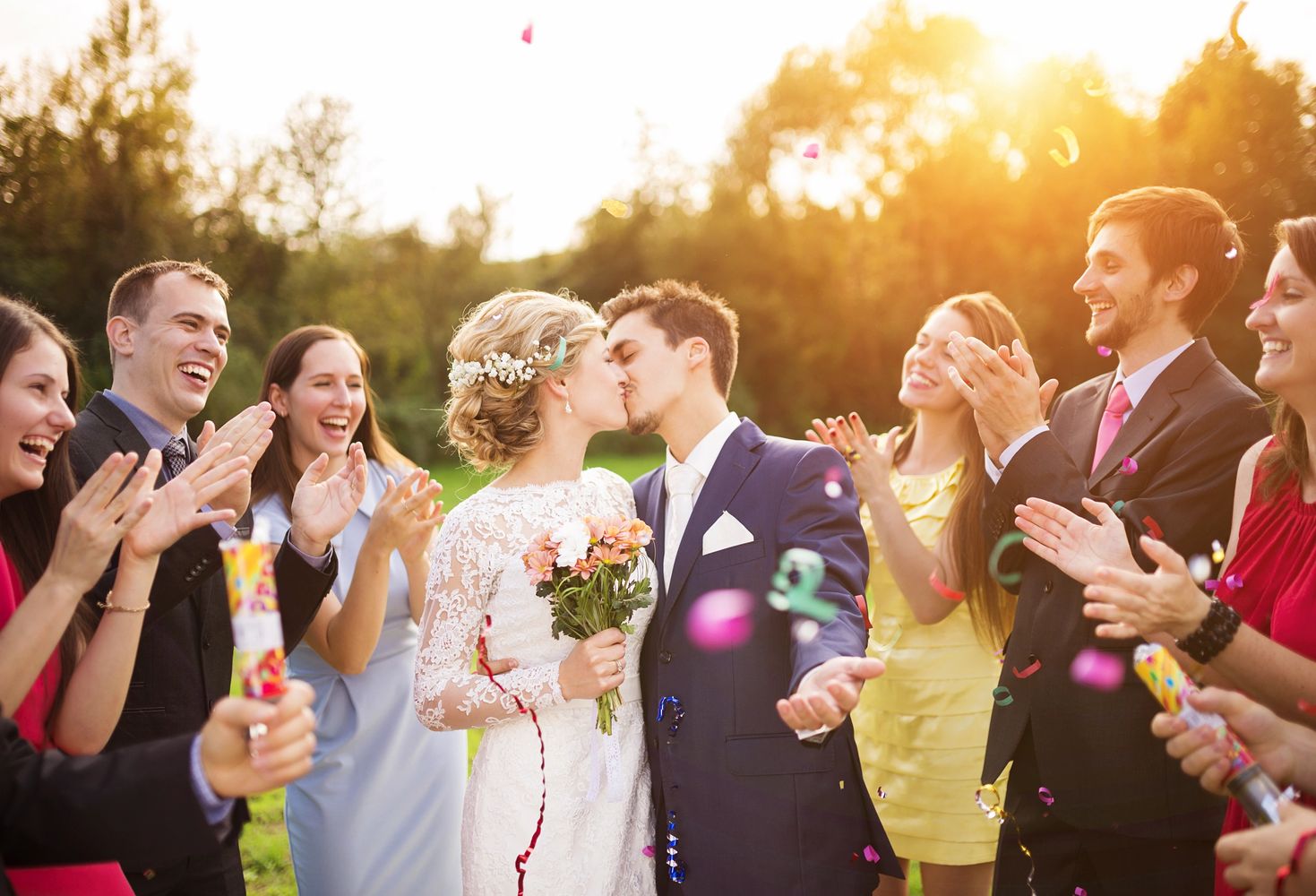 Bride and groom kissing during outdoor Toronto wedding ceremony surrounded by cheering guests.