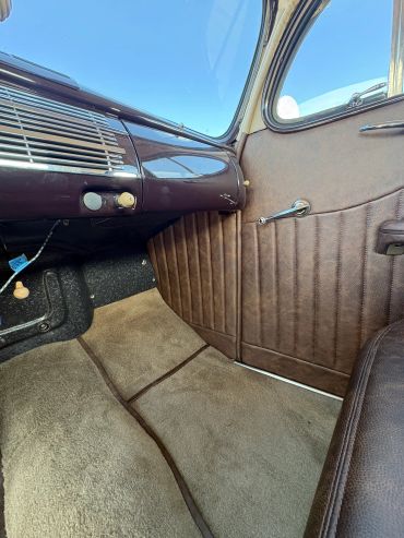 Interior of a vintage car showing door and carpet.