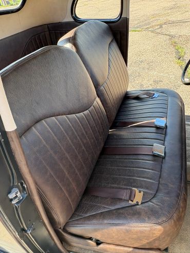 Vintage car interior with brown leather bench seat.
