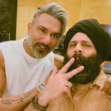 Two men posing closely, one showing a peace sign.