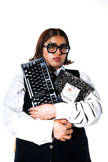 Person holding keyboard and notebook, looking serious.