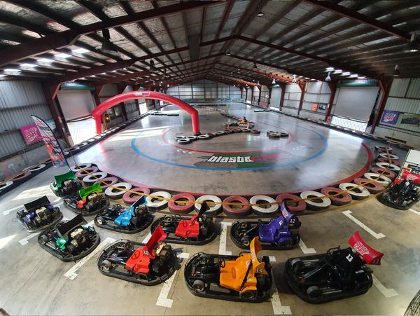 Indoor go-kart racing track with barriers and a red archway.