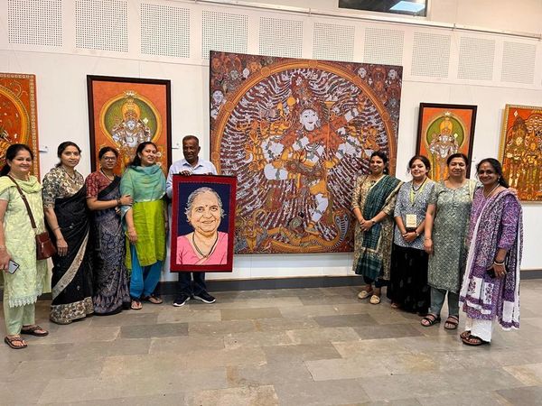 Group of people posing with traditional artwork in a gallery.