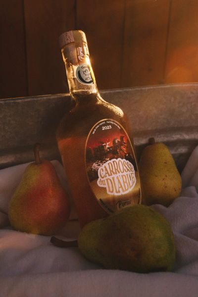 A bottle of Carrosse du Diable with three pears in warm light.