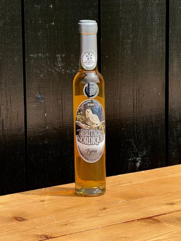 A bottle of Heritage Nordique Pyrias liqueur on a wooden table.
