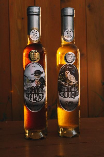Two elegant bottles of award-winning French liqueurs with distinct labels and different colored liquids.