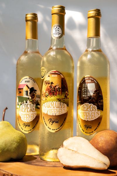Three bottles of Pyrus pear cider with pears on a wooden board.