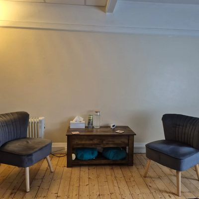 Two gray chairs face a wooden table in a cozy room with wooden flooring.