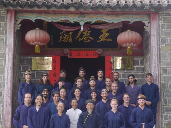 Group photo of people in traditional attire in front of a Chinese building.