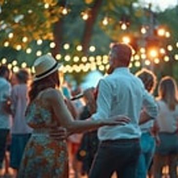 Couple dancing at an outdoor evening party with string lights.