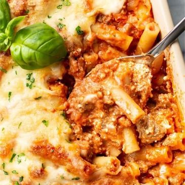 Close-up of cheesy baked ziti with fresh basil garnish.