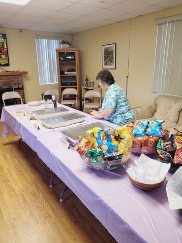 A woman sets up a buffet table with snacks in a cozy room.