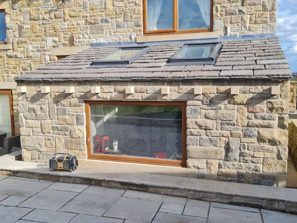 Stone house with skylights and a paved patio area.