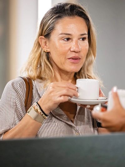 Woman holding a white cup and saucer.