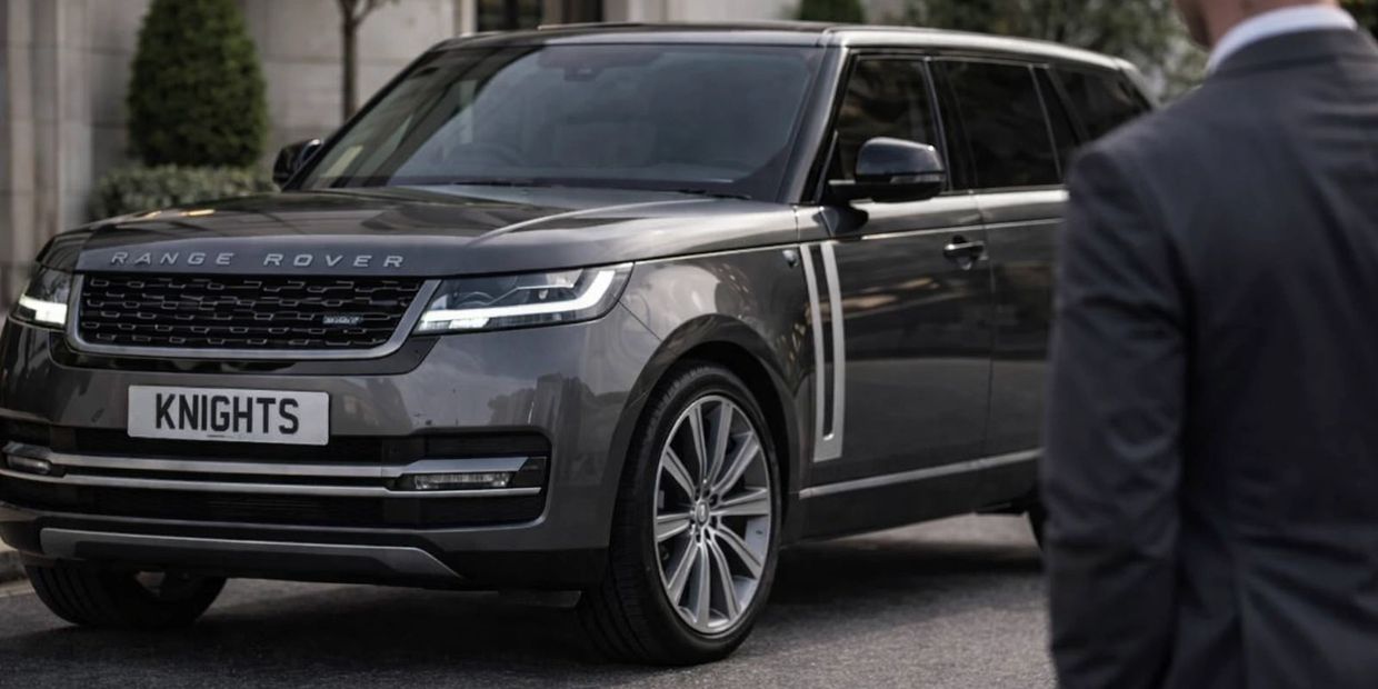 A sleek gray Range Rover with custom license plate 'KNIGHTS' parked on street.