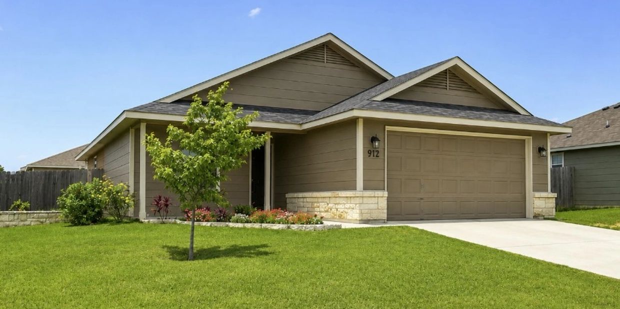 Modern beige house with a well-maintained lawn and single tree.