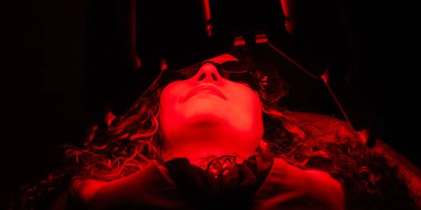 Person illuminated by intense red light looking upwards.