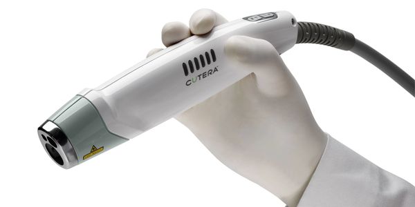 Hand holding a Cutera medical device.