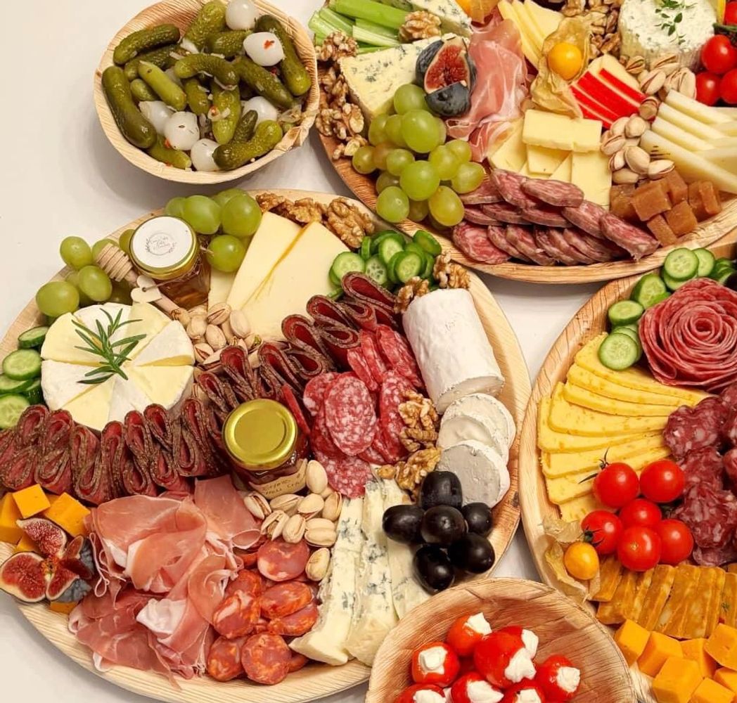 Three elaborate charcuterie boards with assorted meats, cheeses, fruits, nuts, and dips.