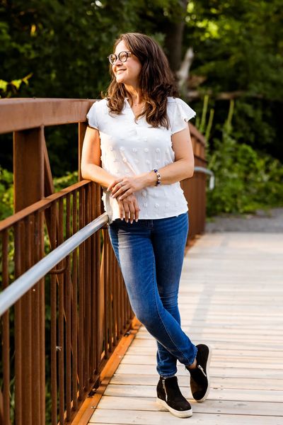 Coach Monica, happy and relaxed, looking out over a bridge at beautiful sunny wooded marsh area