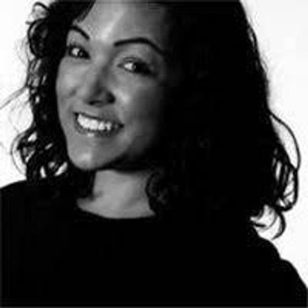 Smiling woman with curly hair in a black top against a white background.