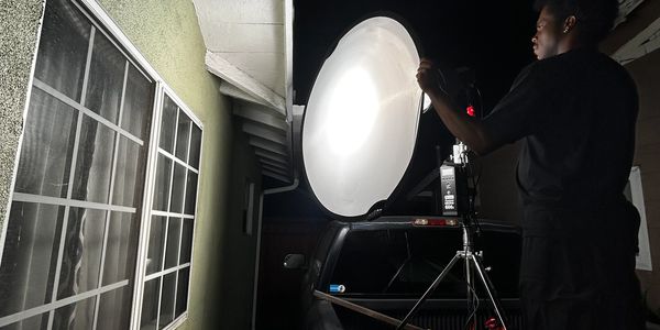 Person adjusting a large studio light diffuser at night beside a building.