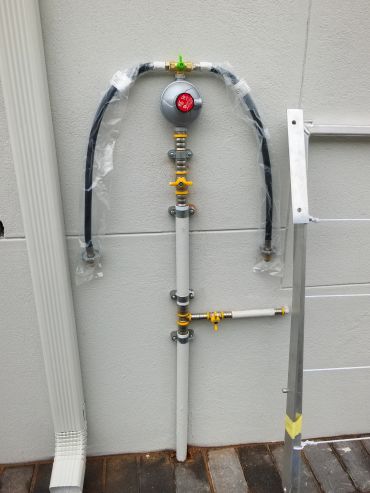 Gas meter with pipes and valves installed on a gray wall.