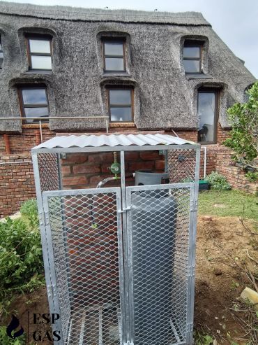 Two gas cylinders secured in a metal cage outdoors.