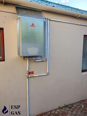 Gas meter and pipes installed on a beige wall.