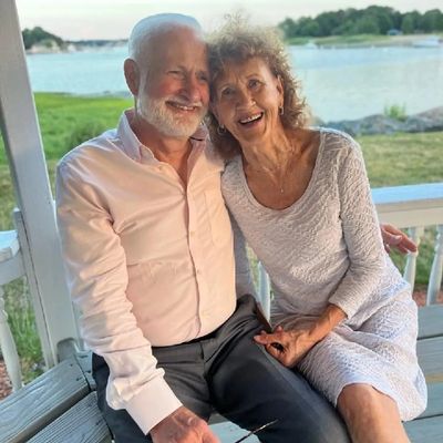 Elderly couple smiling and enjoying a peaceful moment outdoors by the water.