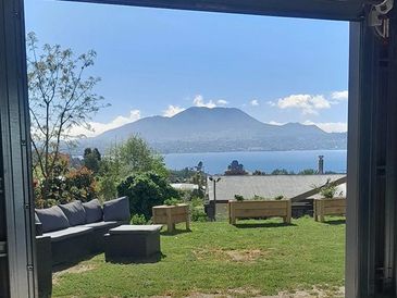 View from a garage opening to a grassy yard and distant mountains across water.