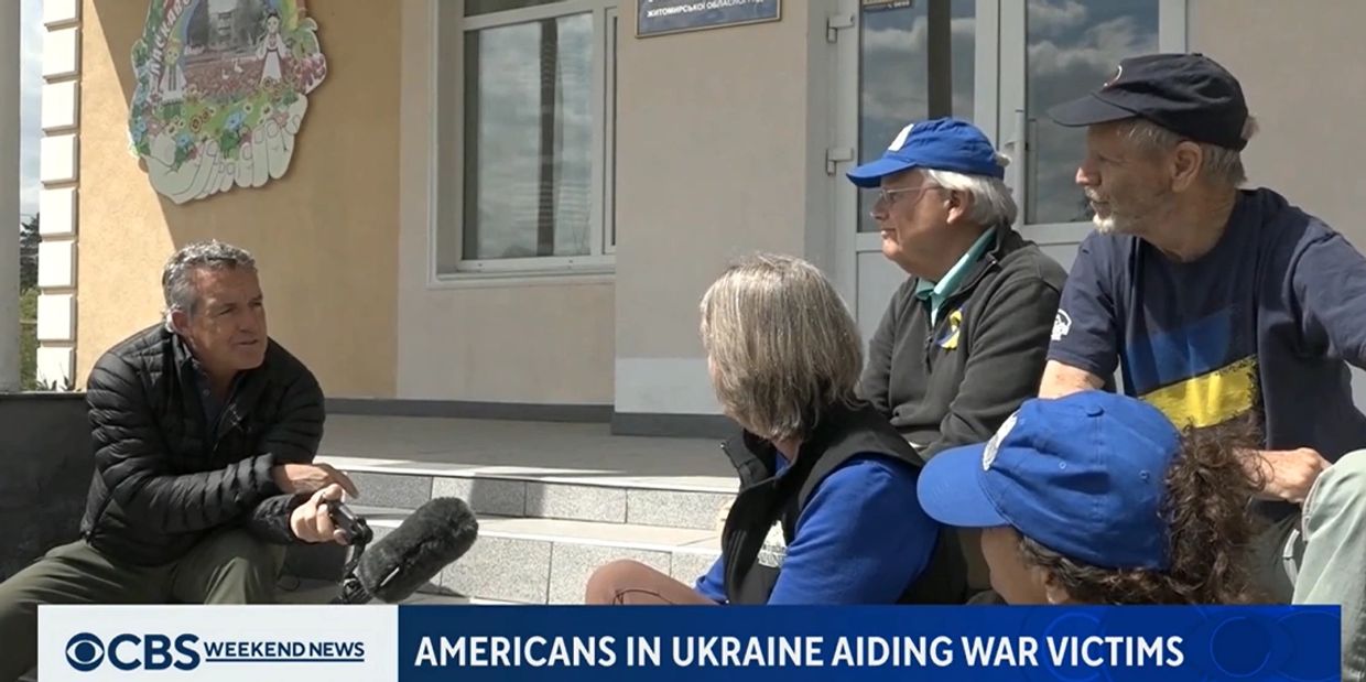 Americans in Ukraine discussing aid efforts for war victims outdoors.