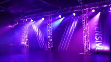 Stage lighting with purple beams and metal trusses.