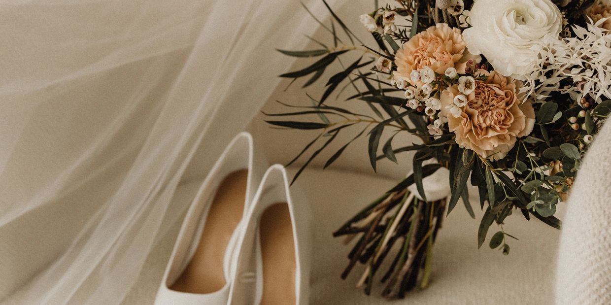 Elegant bridal bouquet and white shoes beside a wedding veil.