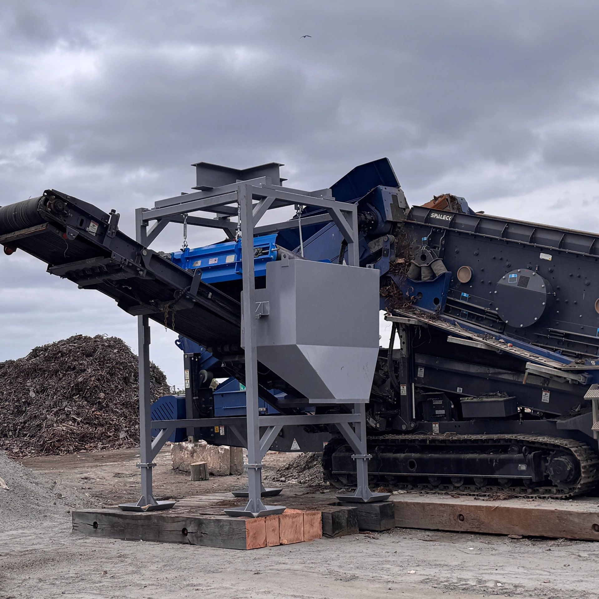 Industrial conveyor system with machinery for material processing under a cloudy sky.