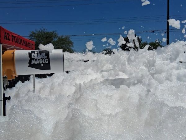 Foam machine creating thick foam outdoors on a sunny day.