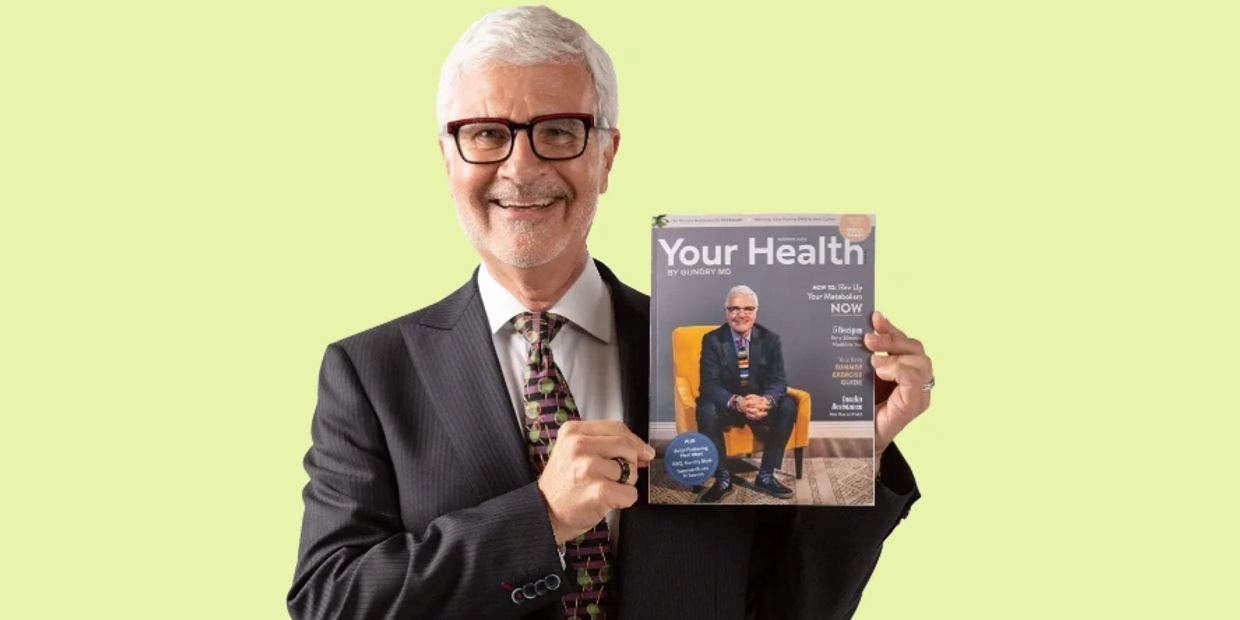 Smiling elderly man in a suit holding a health magazine featuring himself on the cover.