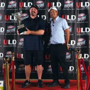 Two men standing on a podium, one holding a trophy.