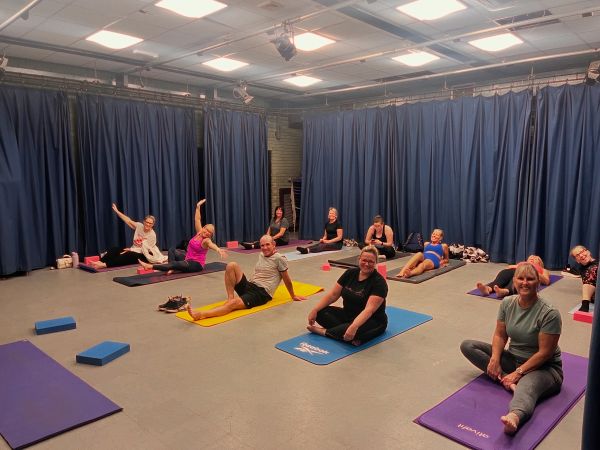Group yoga session with participants on mats in a spacious room.