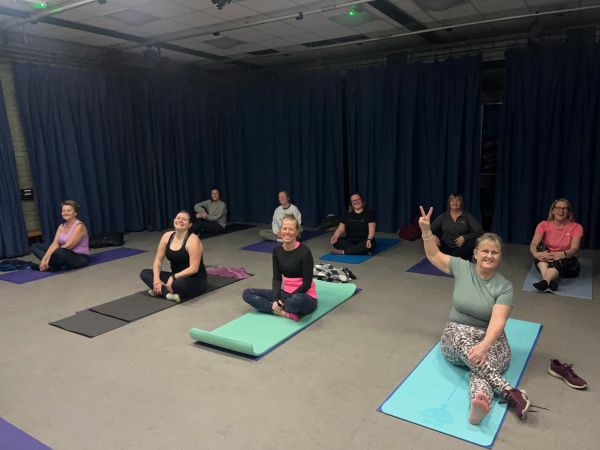 Group of women sitting on yoga mats in a studio.