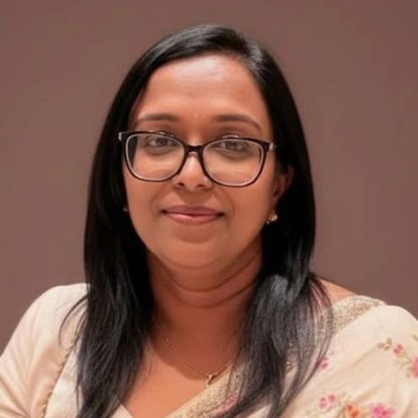 Woman with glasses and black hair smiling gently.
