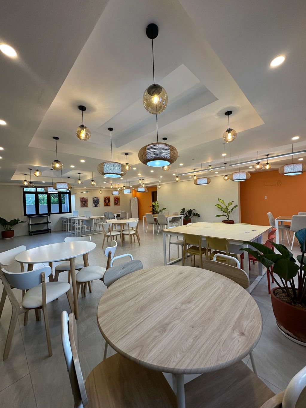 Modern dining room with wooden tables and stylish hanging lights.