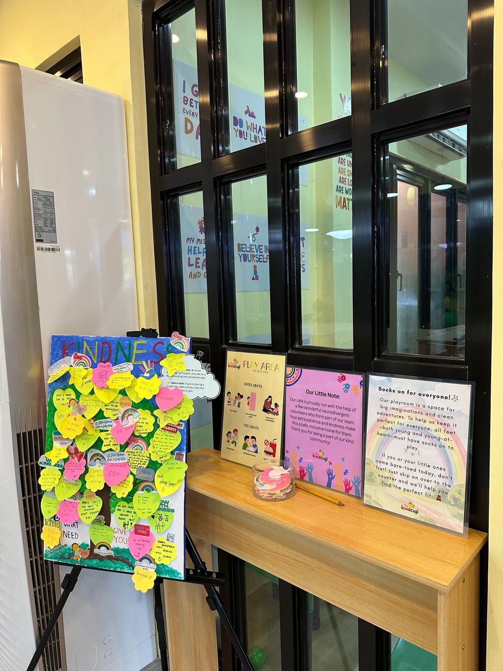 A kindness board with colorful notes and instructions for a play area.