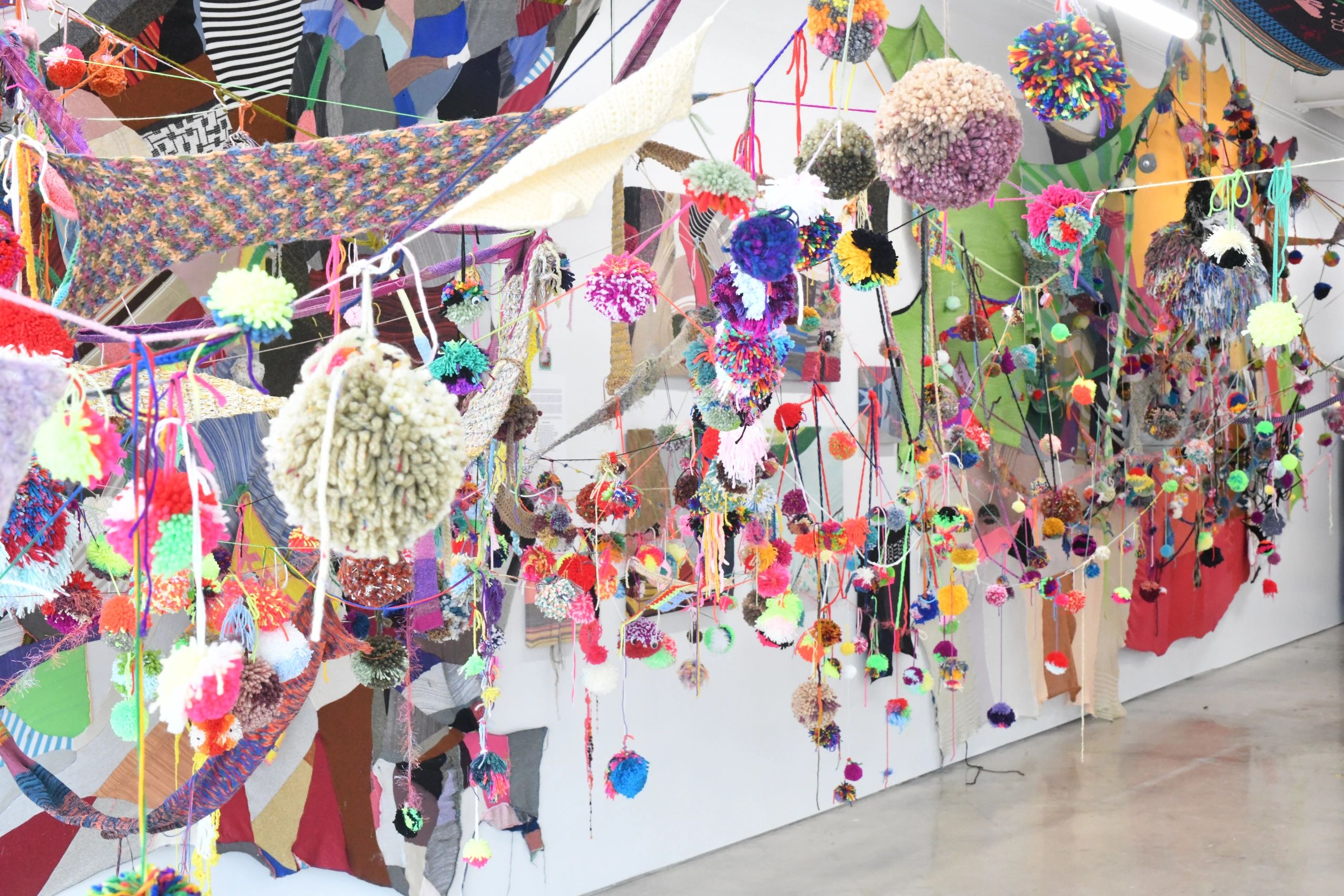 Colorful yarn pom-poms hanging in an art installation.