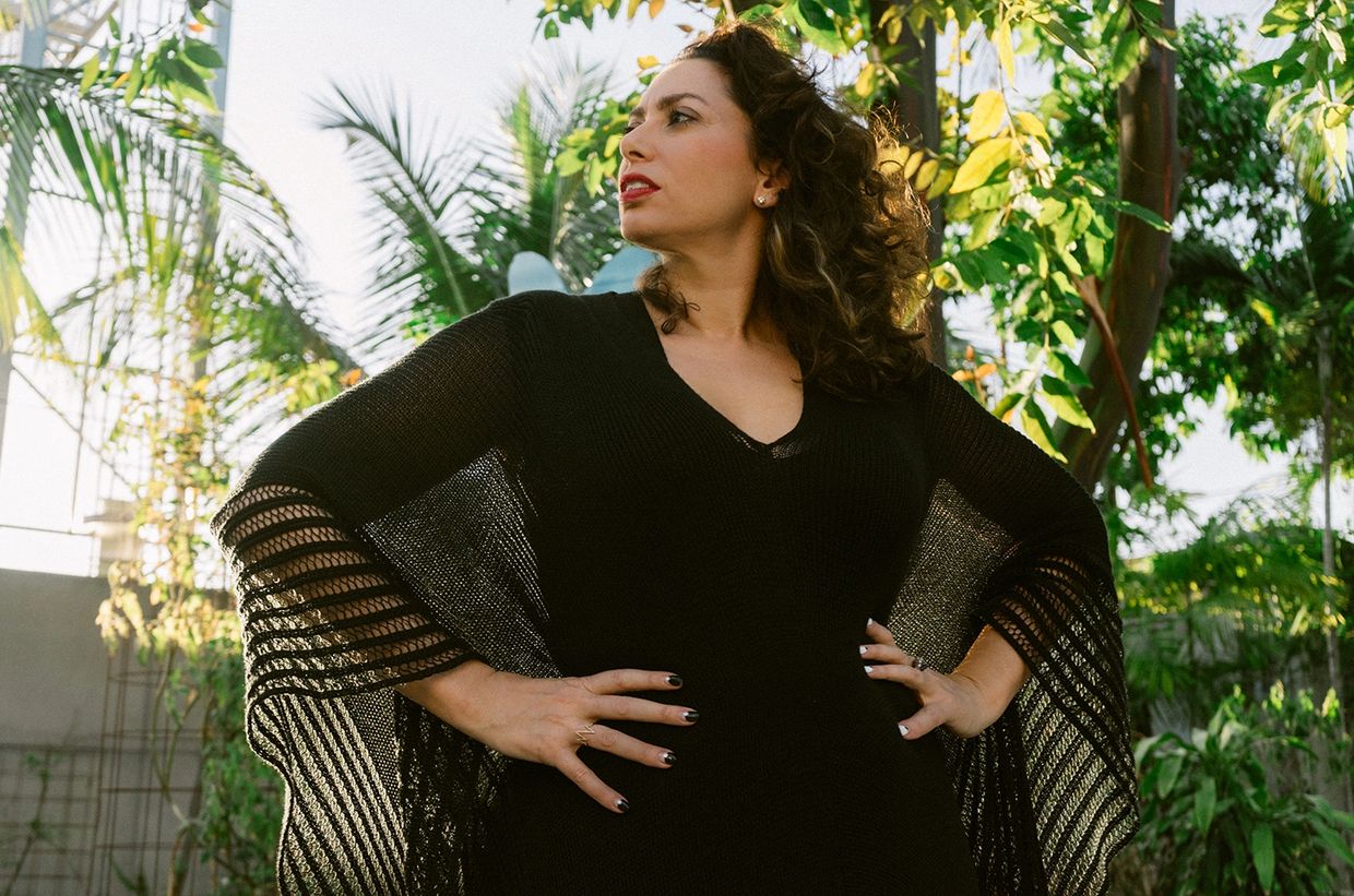 Confident woman in black dress with hands on hips.