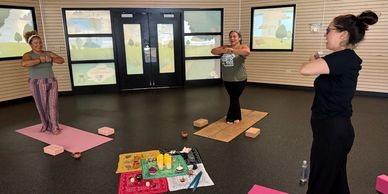 Three women practicing yoga indoors with mats and candles.