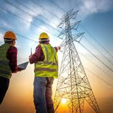 Engineers inspecting power lines during sunset.